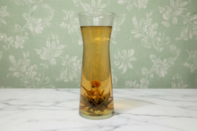 Clear glass vase with floral arrangement on a textured surface
