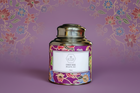Decorative tea canister with colorful design and 'ETTE' branding on a floral patterned background.