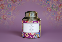 Decorative tea canister with colorful design and 'ETTE' branding on a floral patterned background.