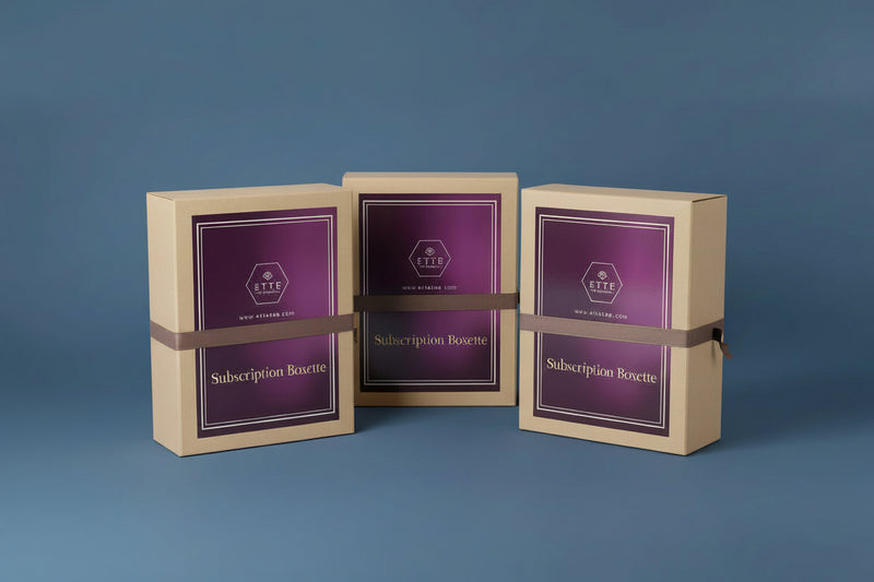 Box with purple label and 'ETTE' branding on a wooden surface with a plant in the corner.