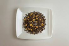 White square plate with dried tea leaves and 'ETTE' branding on a light gray background