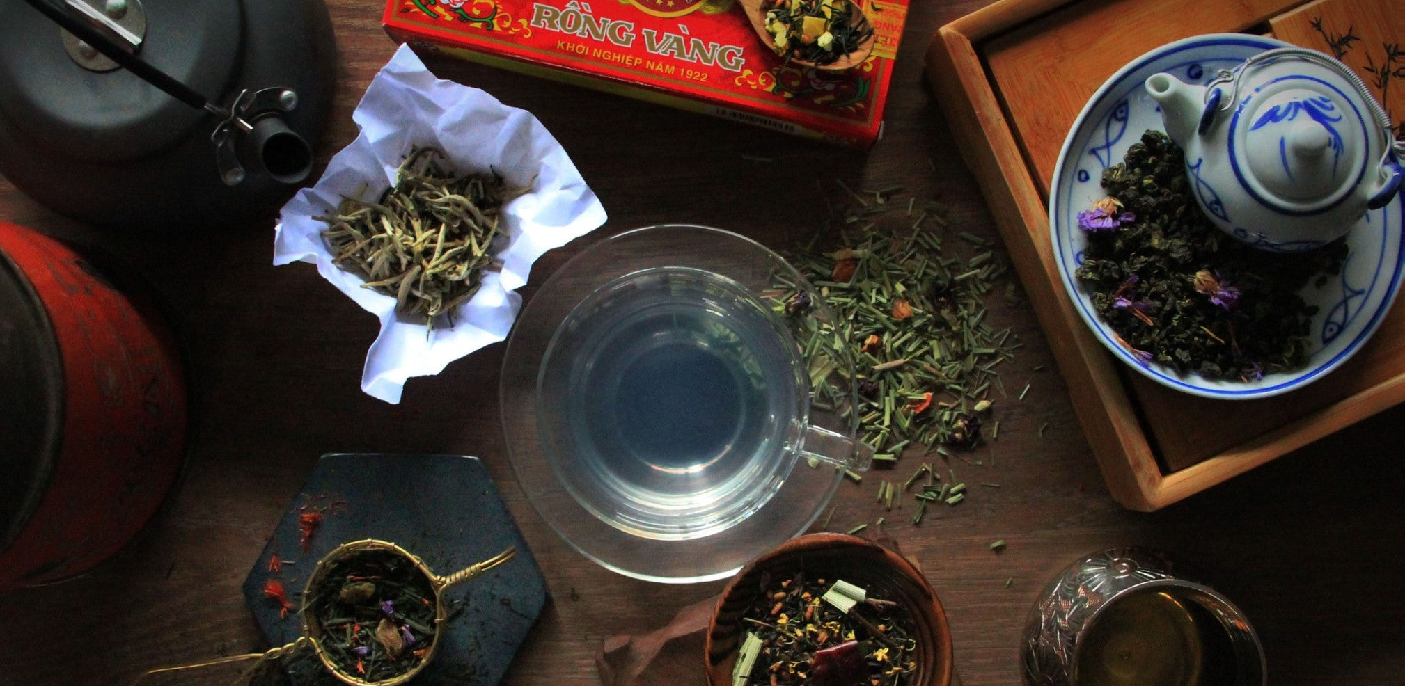 Mood shot of Singapore tea blends and pure teas with a brewed cup of Kebaya blue tea in the middle. 