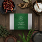 Box labeled 'ETTE' surrounded by dried red chilies, leaves, and a plant on a wooden surface.