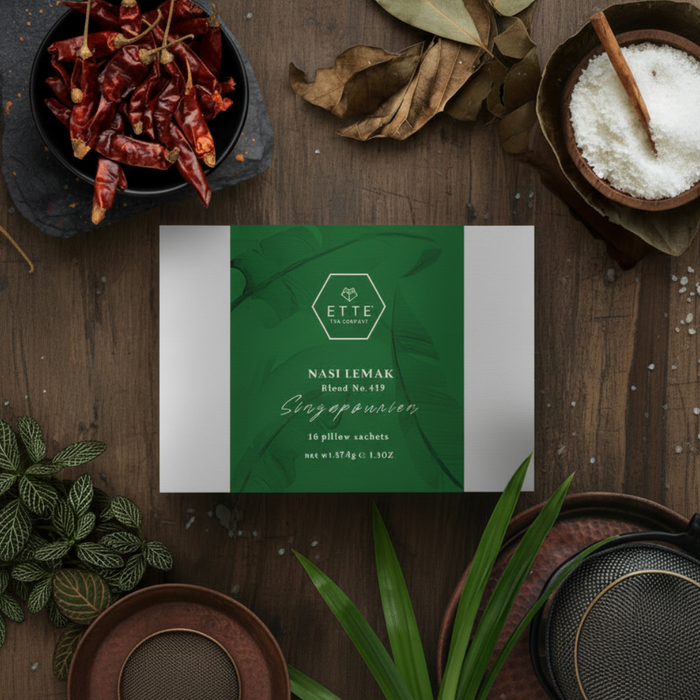 Box labeled 'ETTE' surrounded by dried red chilies, leaves, and a plant on a wooden surface.