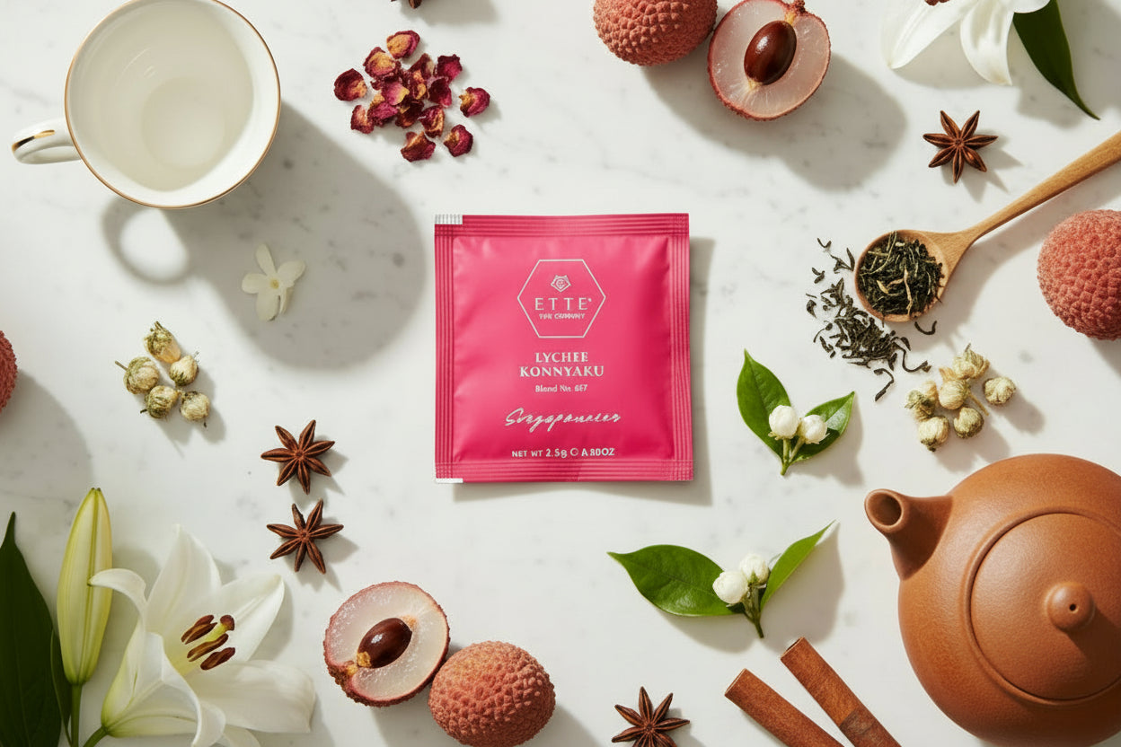 Tea packaging with lychees, a teacup, and a teapot on a marble surface.