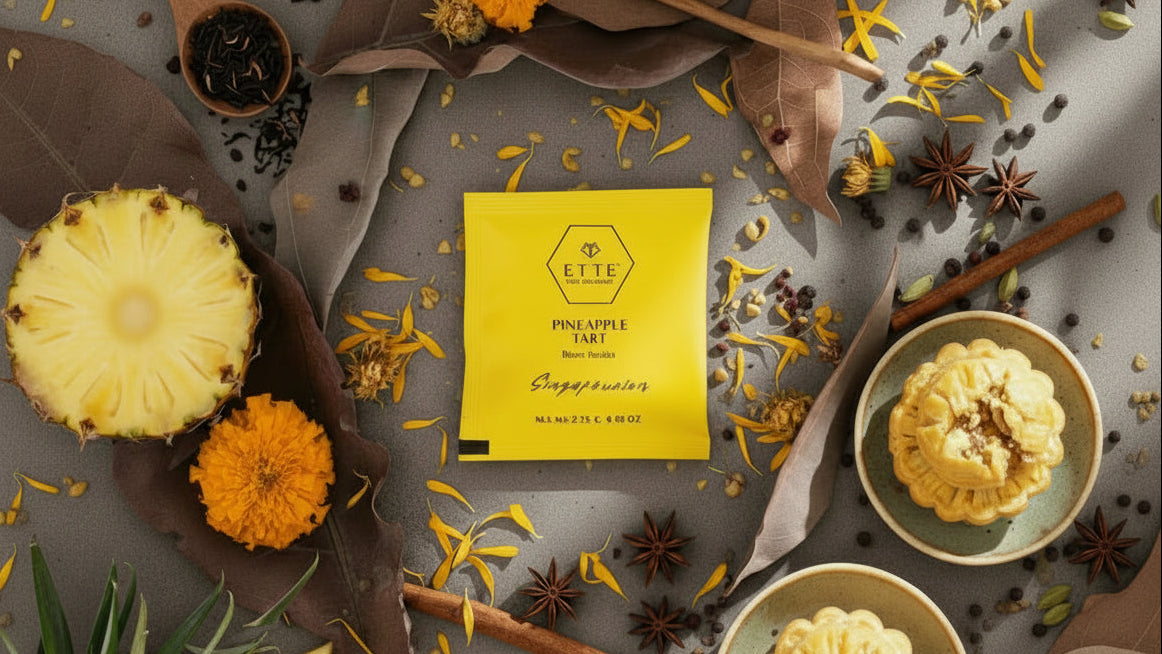 Yellow tea package with pineapples, flowers, and spices on a gray surface